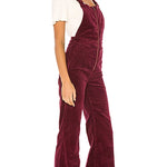 Woman wearing a burgundy corduroy jumpsuit on a white background