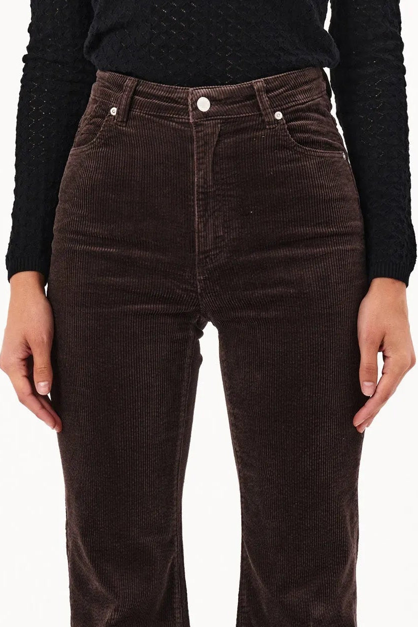 Brown flared jeans worn by a person on a white background