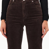 Brown flared jeans worn by a person on a white background