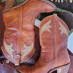 Pair of brown cowboy boots with intricate designs on a saddle