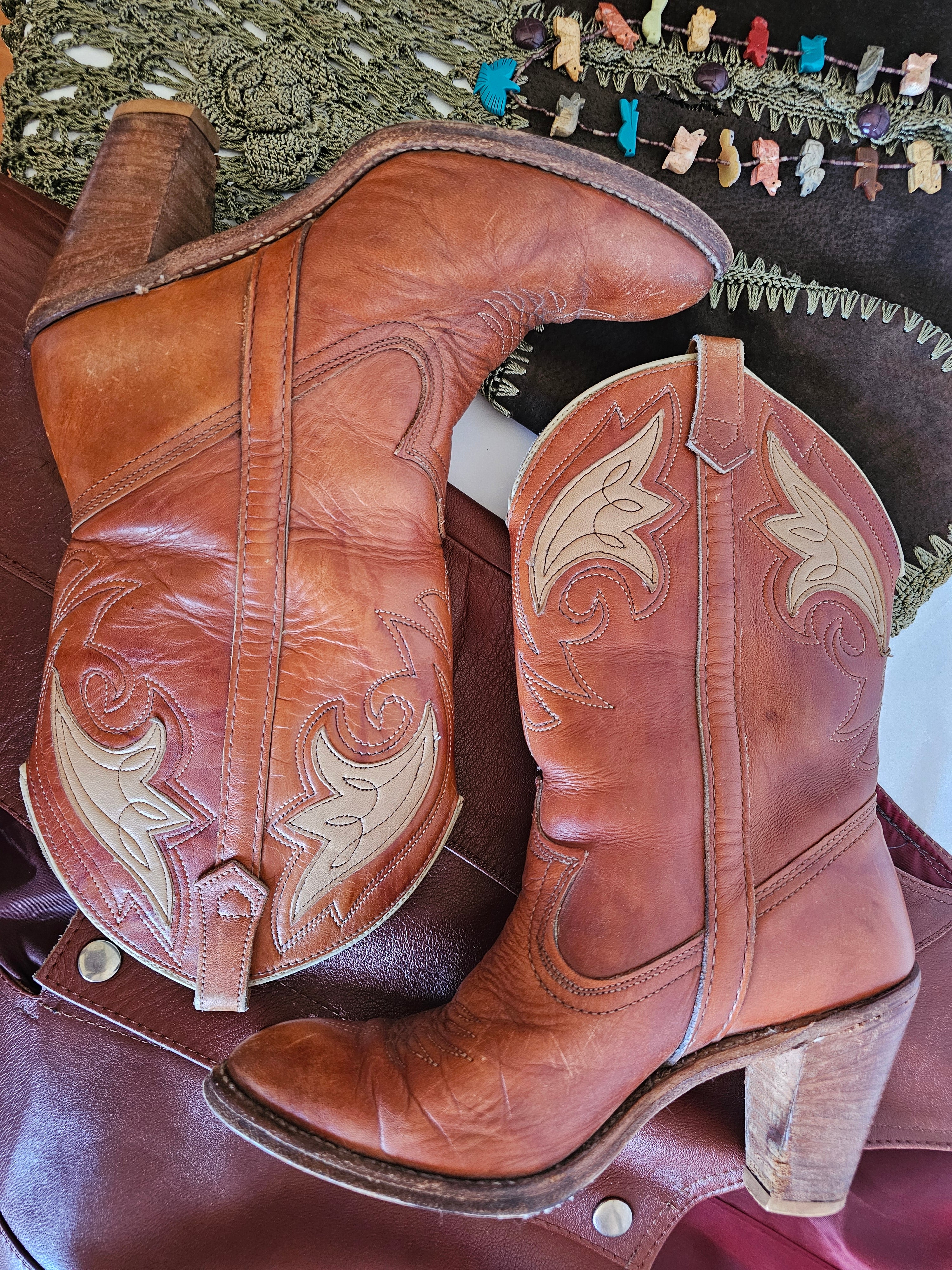 Pair of brown cowboy boots with intricate designs on a saddle
