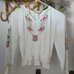 White blouse with floral embroidery on a white background
