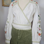 Traditional outfit with white blouse and green skirt on a mannequin against a neutral background