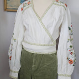 Traditional outfit with white blouse and green skirt on a mannequin against a neutral background