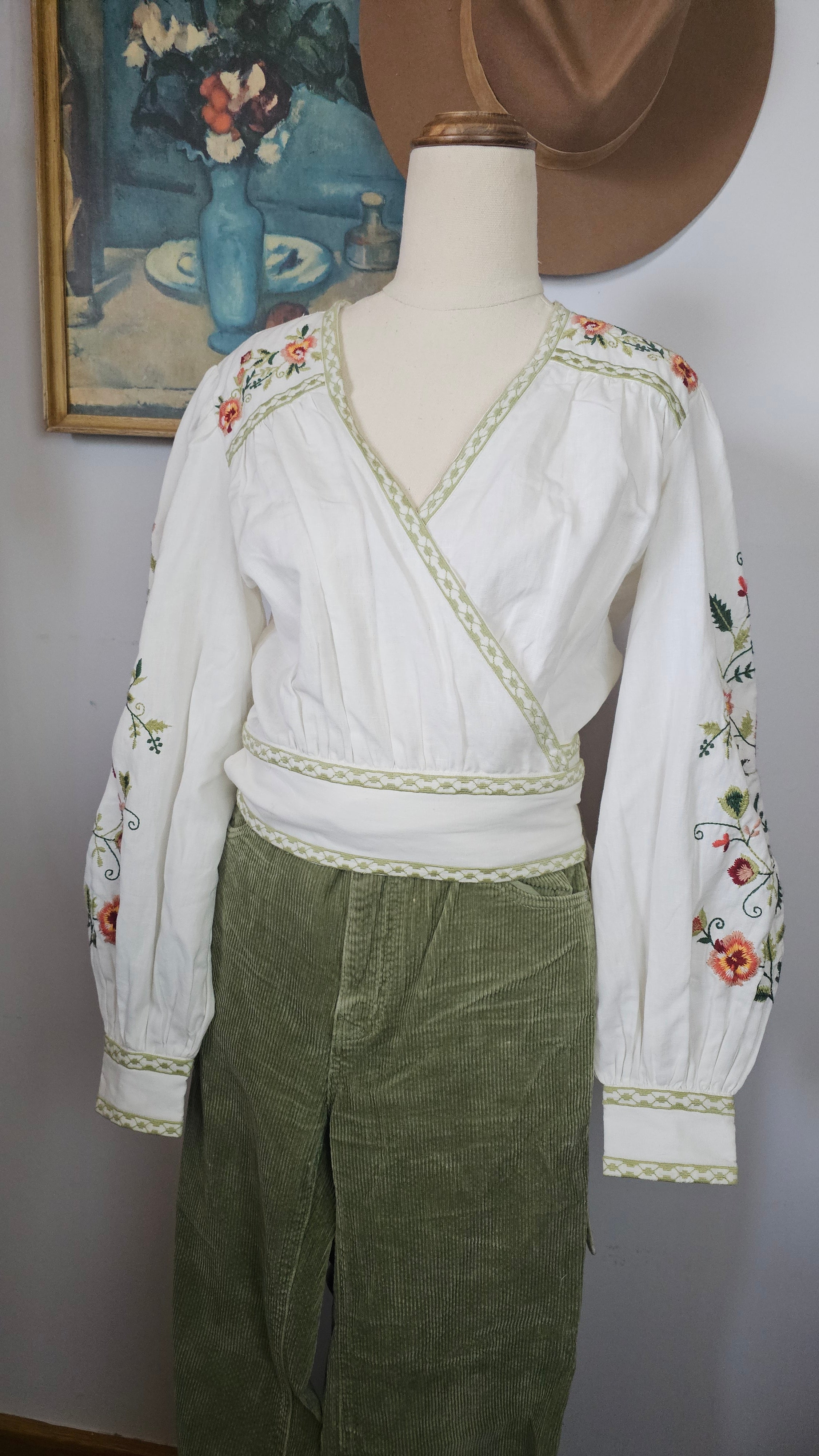 Traditional outfit with white blouse and green skirt on a mannequin against a neutral background