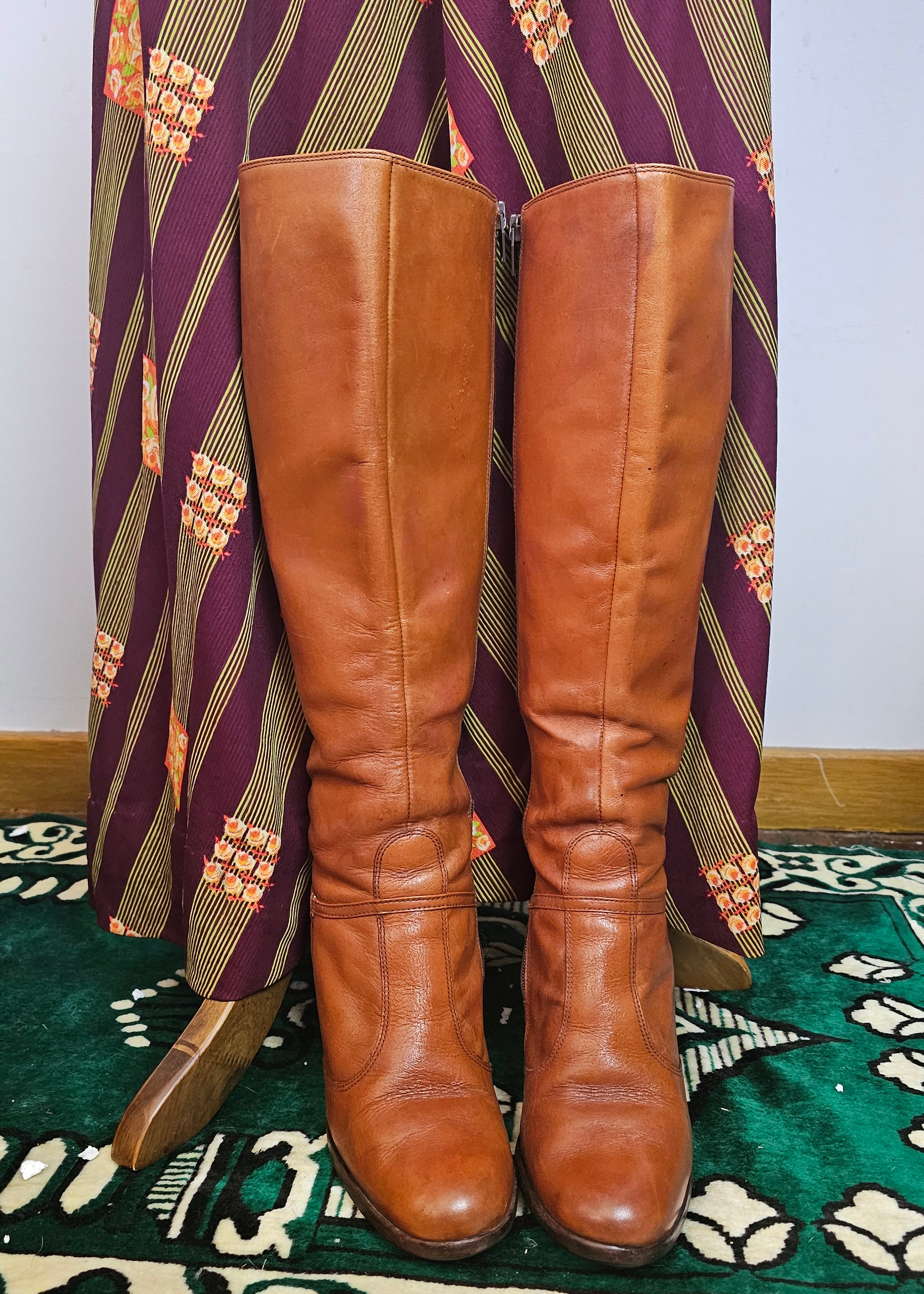 Pair of brown leather knee-high boots on a patterned surface