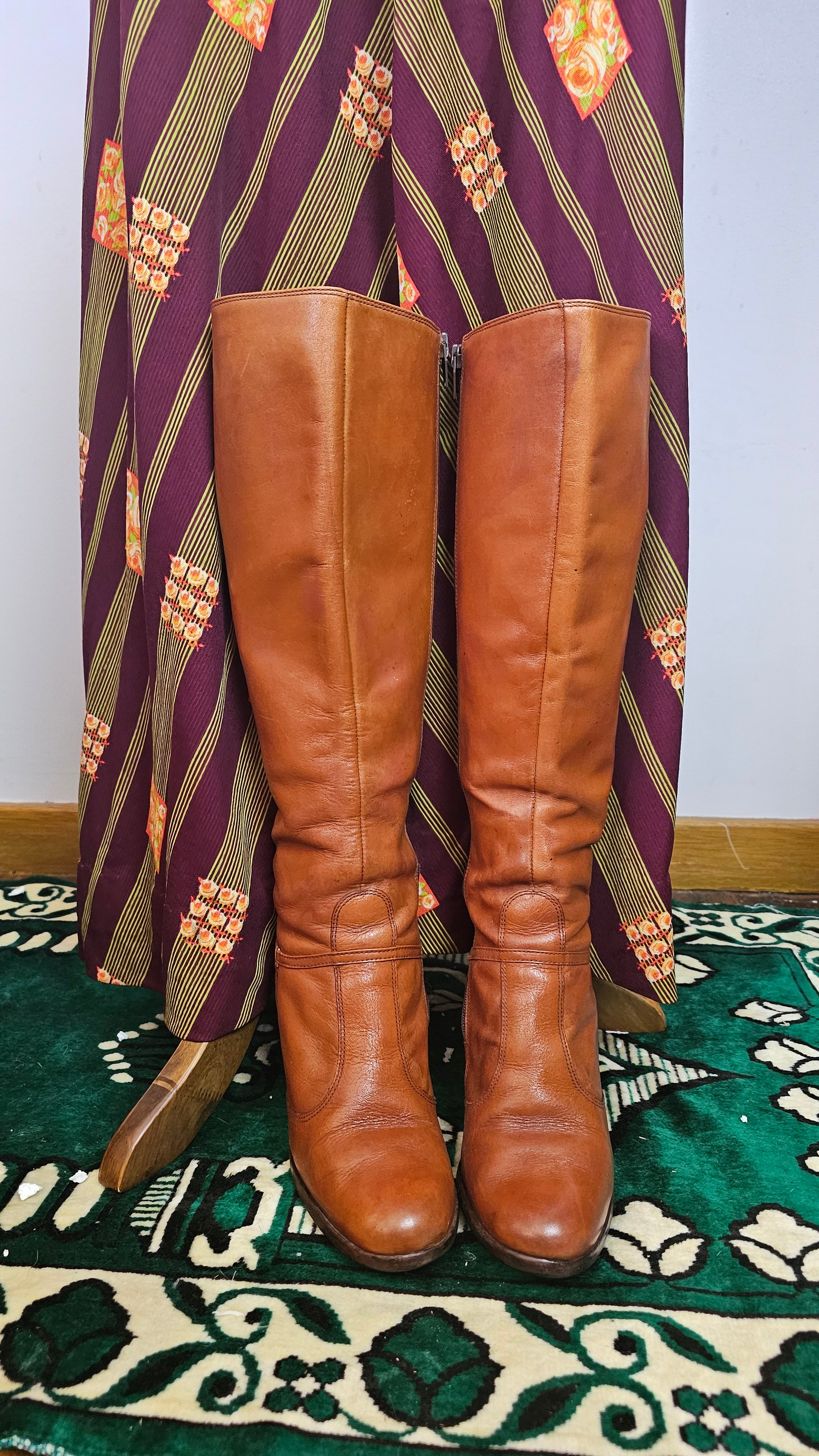 Pair of brown leather knee-high boots on a patterned surface