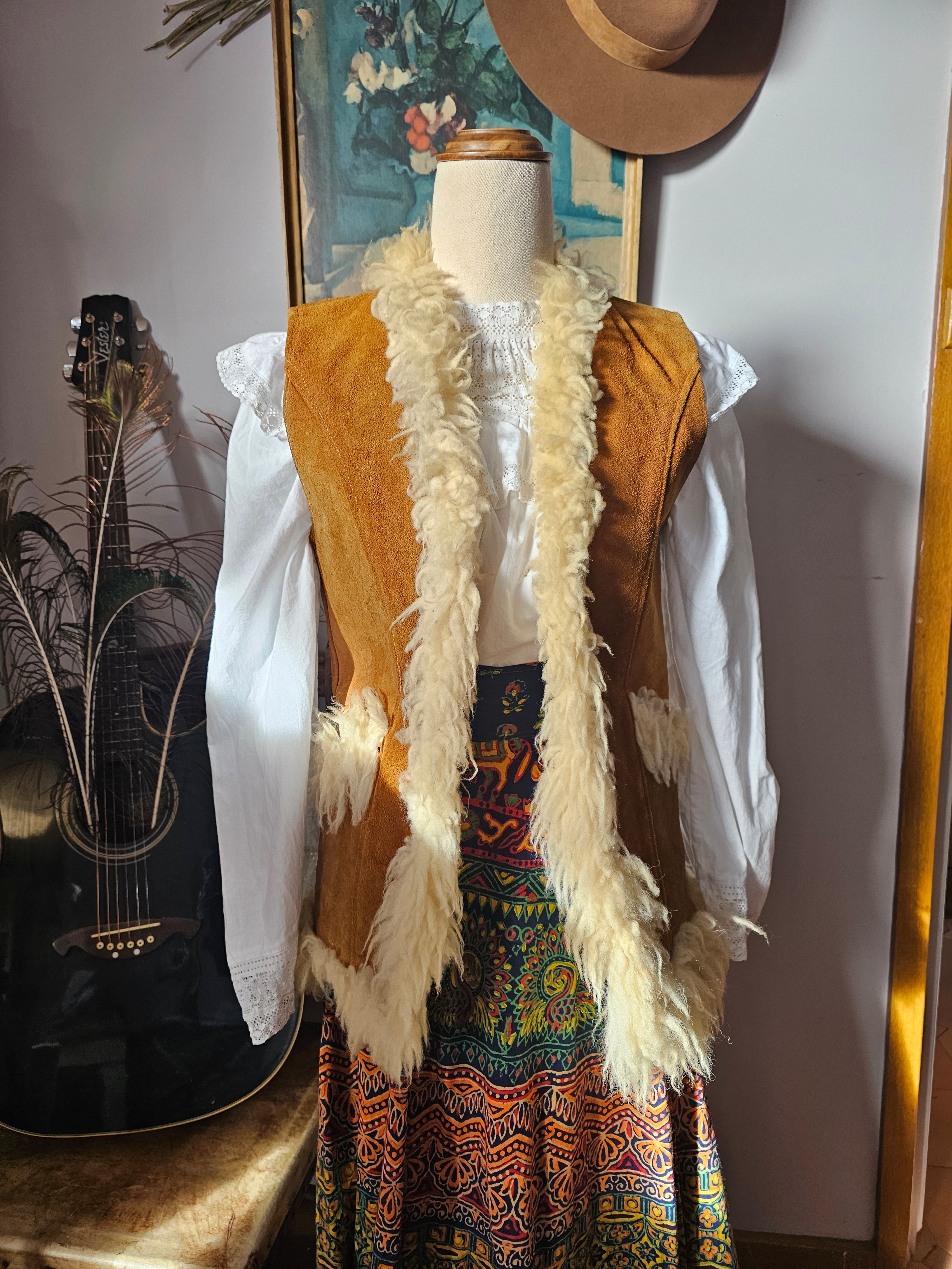 Decorative staff with feathers and patterns on a stand with a guitar in the background