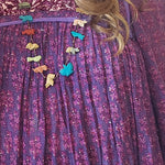 Purple dress with colorful floral embellishments worn by a person.