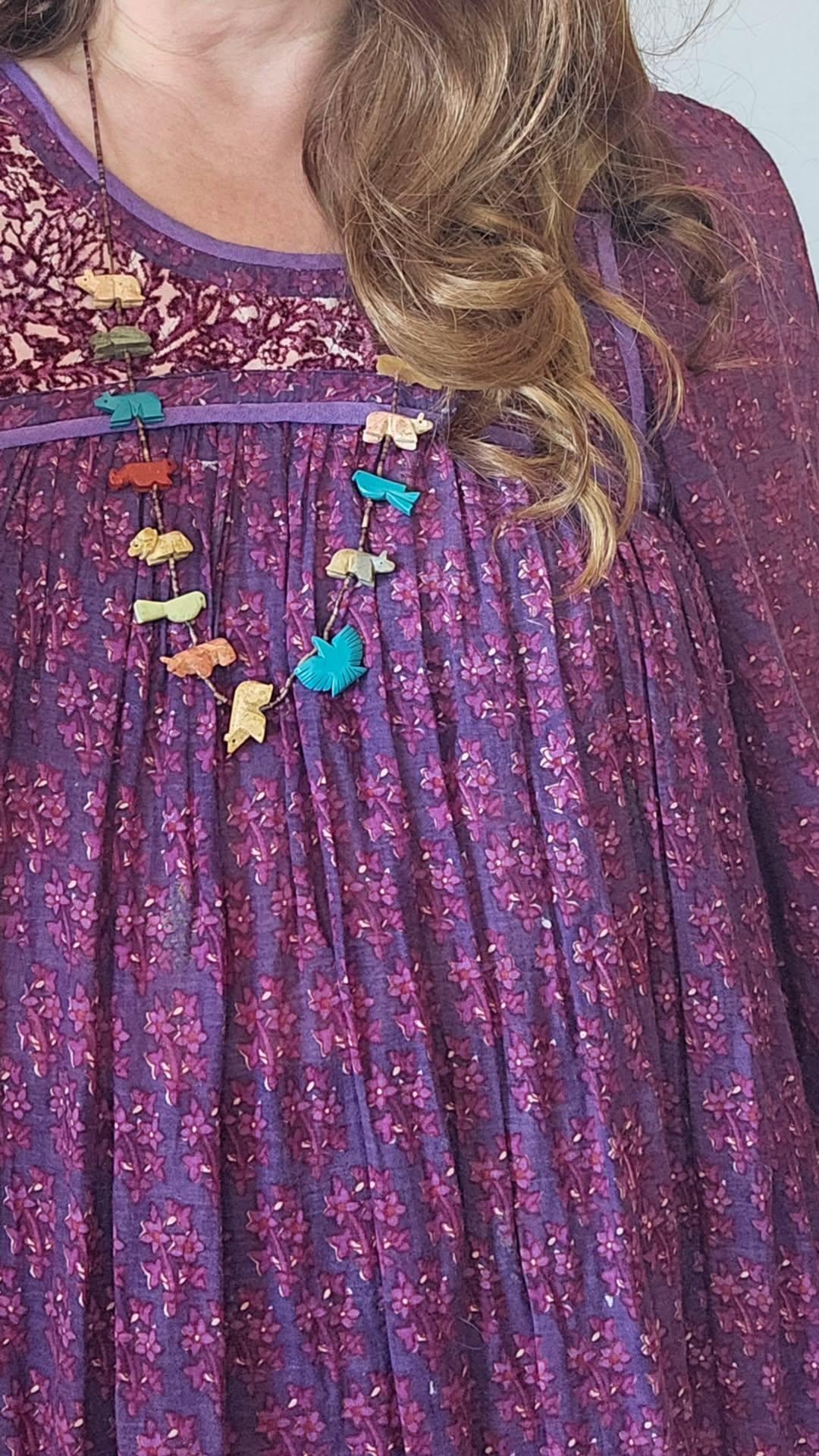 Purple dress with colorful floral embellishments worn by a person.