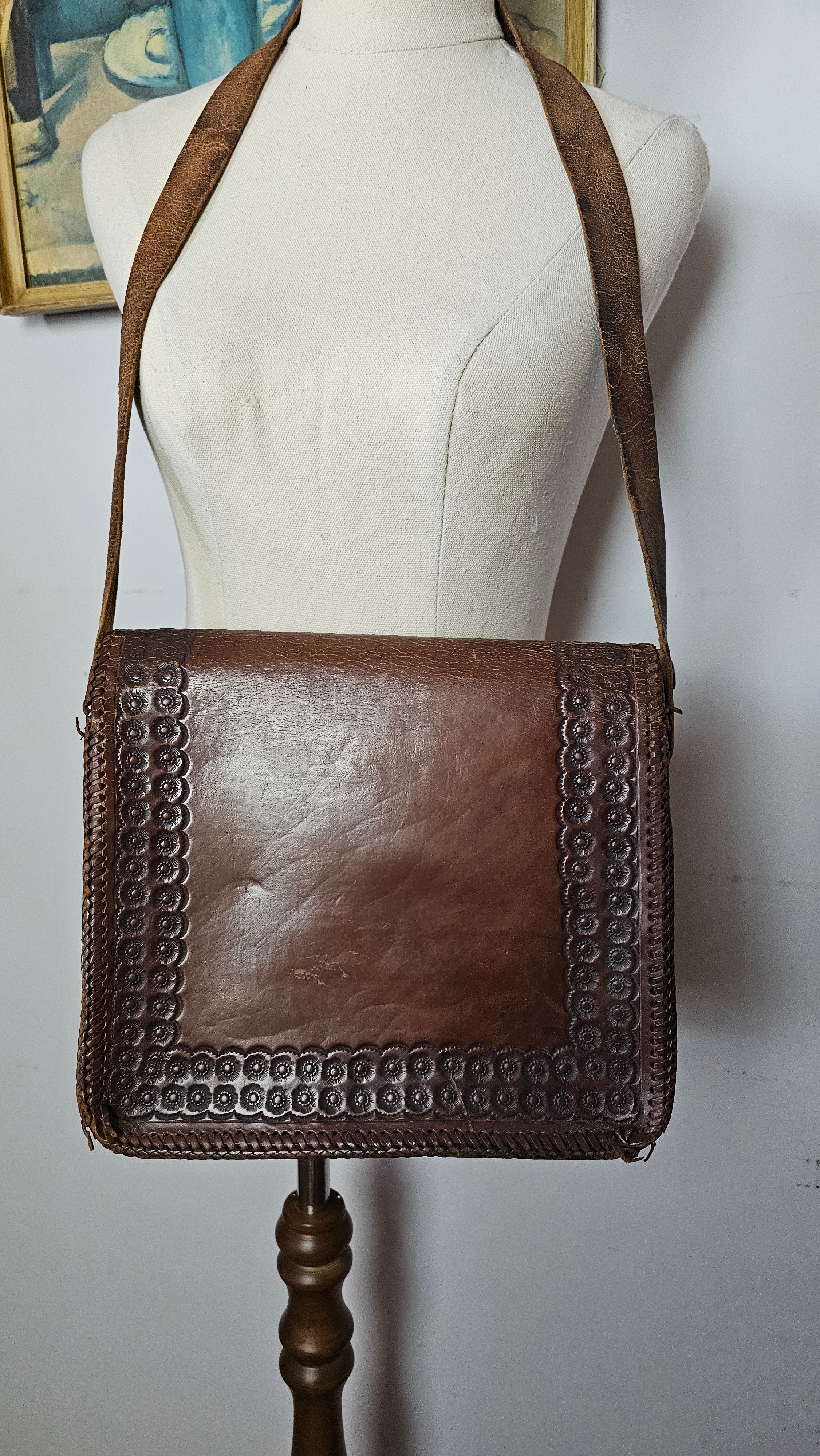 Brown leather handbag with studded detail on a mannequin against a white background