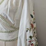 White garment with floral embroidery on a white background