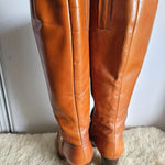 Brown leather pants on a white surface with a textured beige rug.
