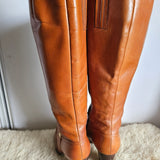 Brown leather pants on a white surface with a textured beige rug.