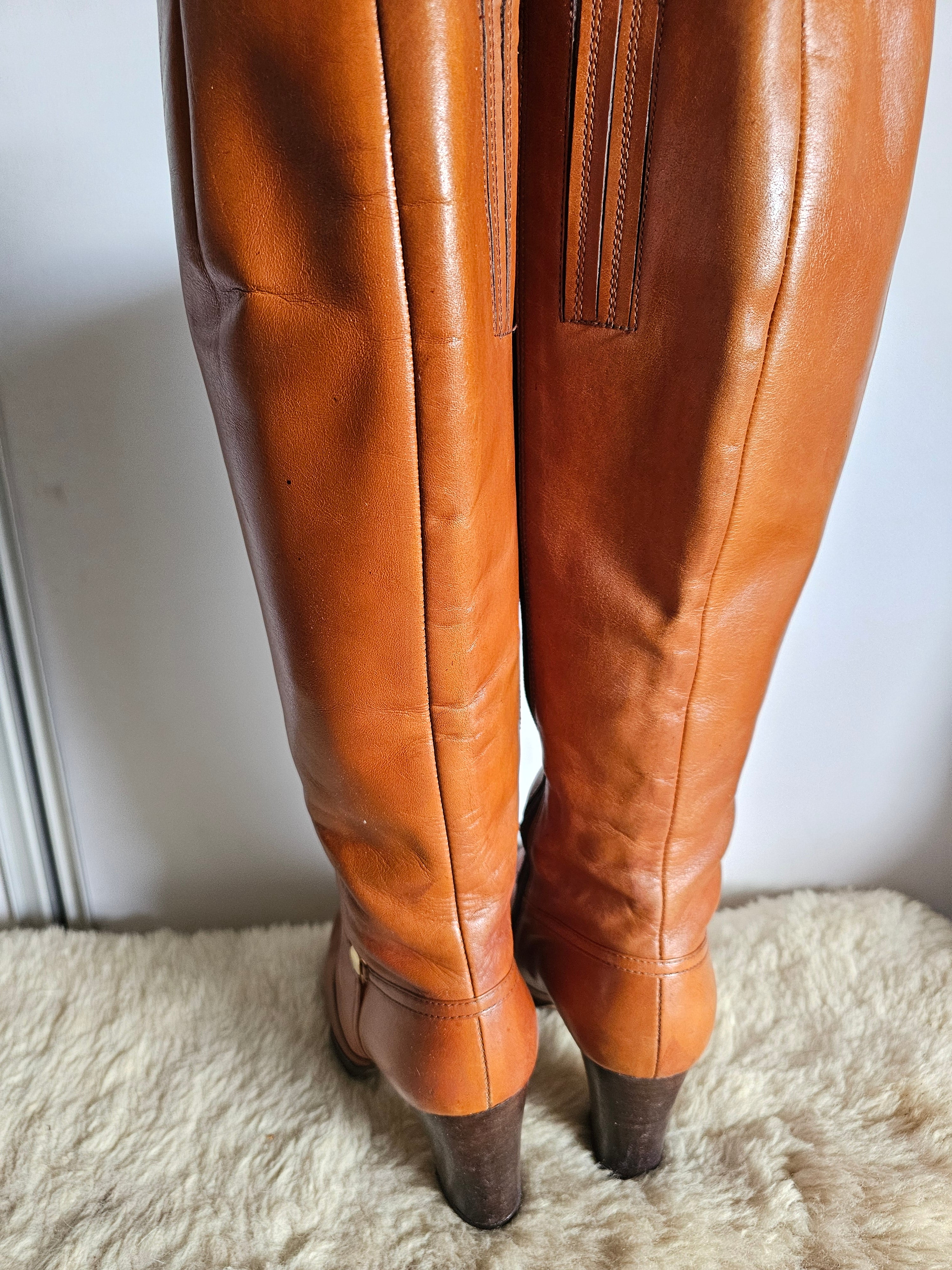 Brown leather pants on a white surface with a textured beige rug.