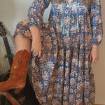 Model wearing Property of Zephyr – Sienna Long Layer Dress in blue and cream paisley print with tassel neckline and balloon sleeves, size small.