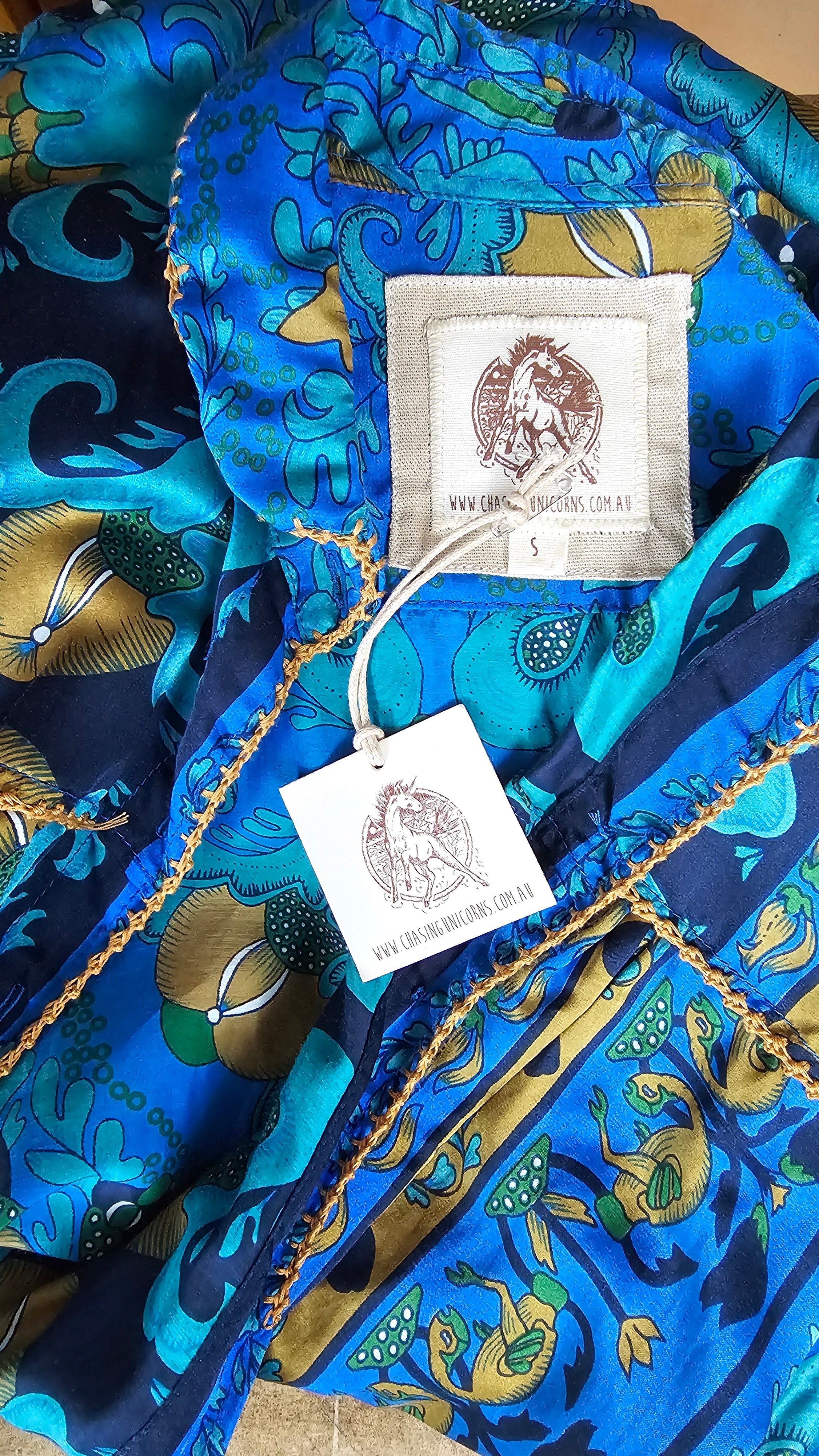 Close-up of a blue patterned fabric with gold accents and a visible brand tag.