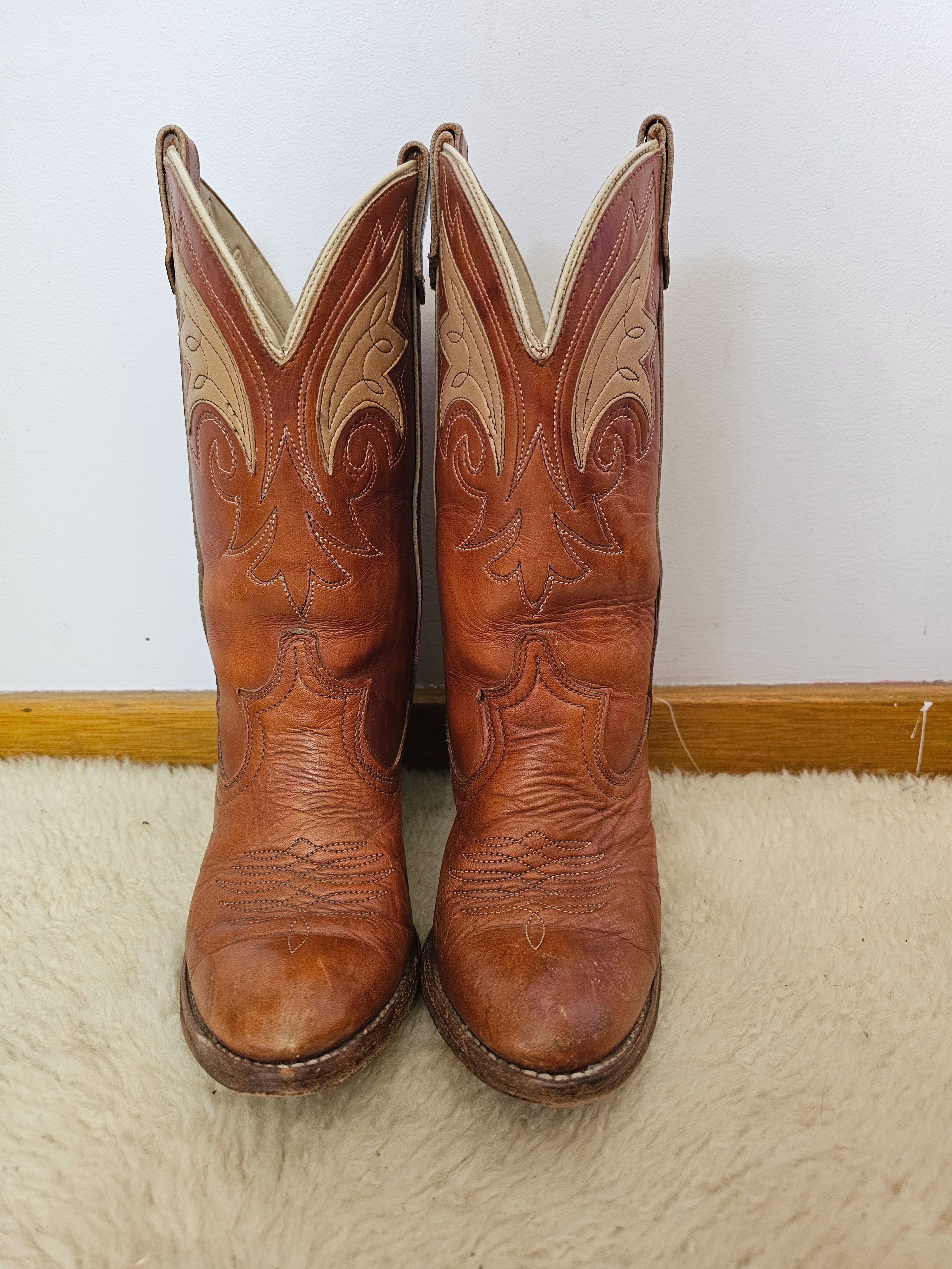Pair of brown cowboy boots with intricate designs on a white background