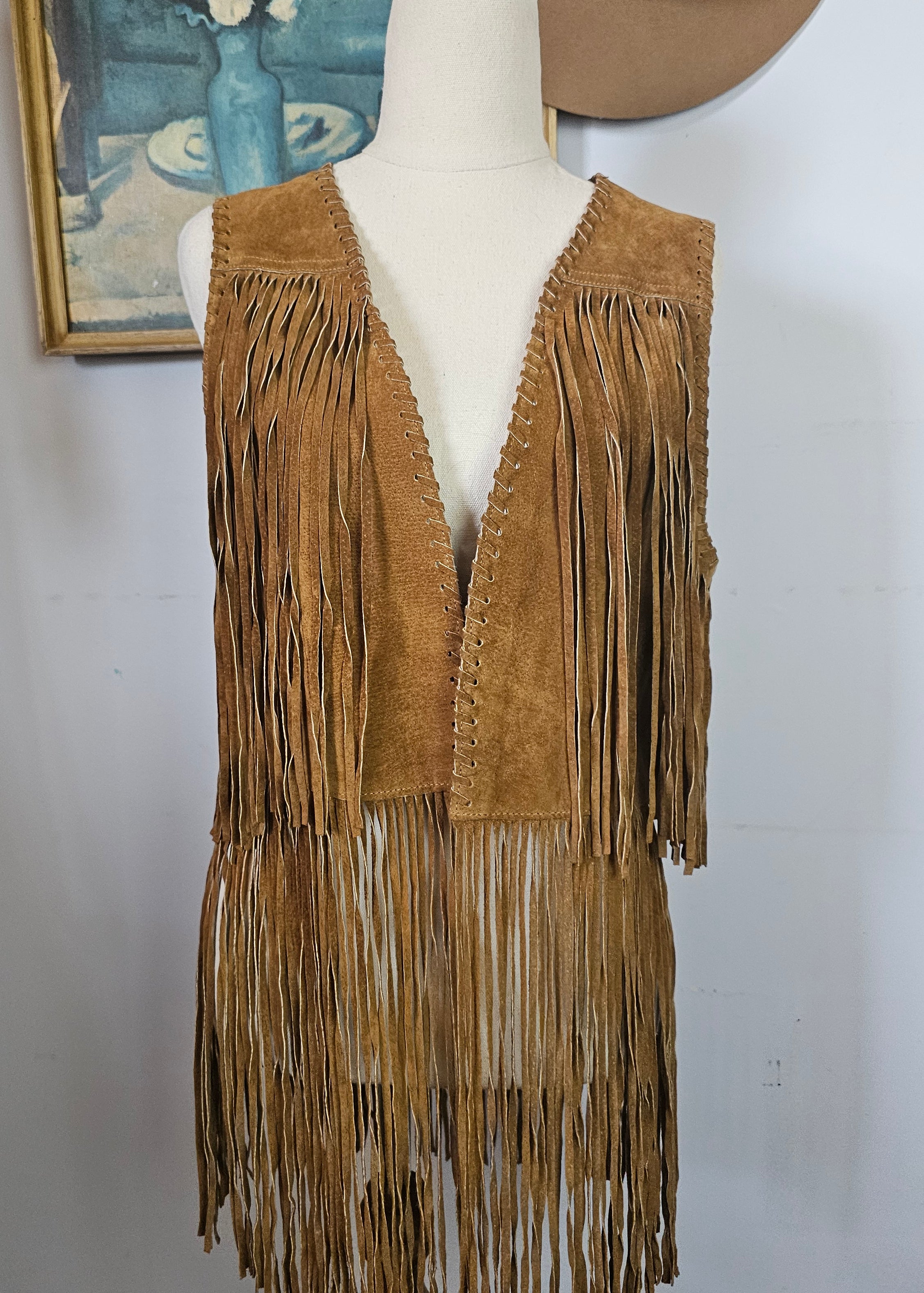 Brown fringed jacket on a mannequin with a plain background