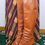 Brown leather knee-high boots on a patterned chair