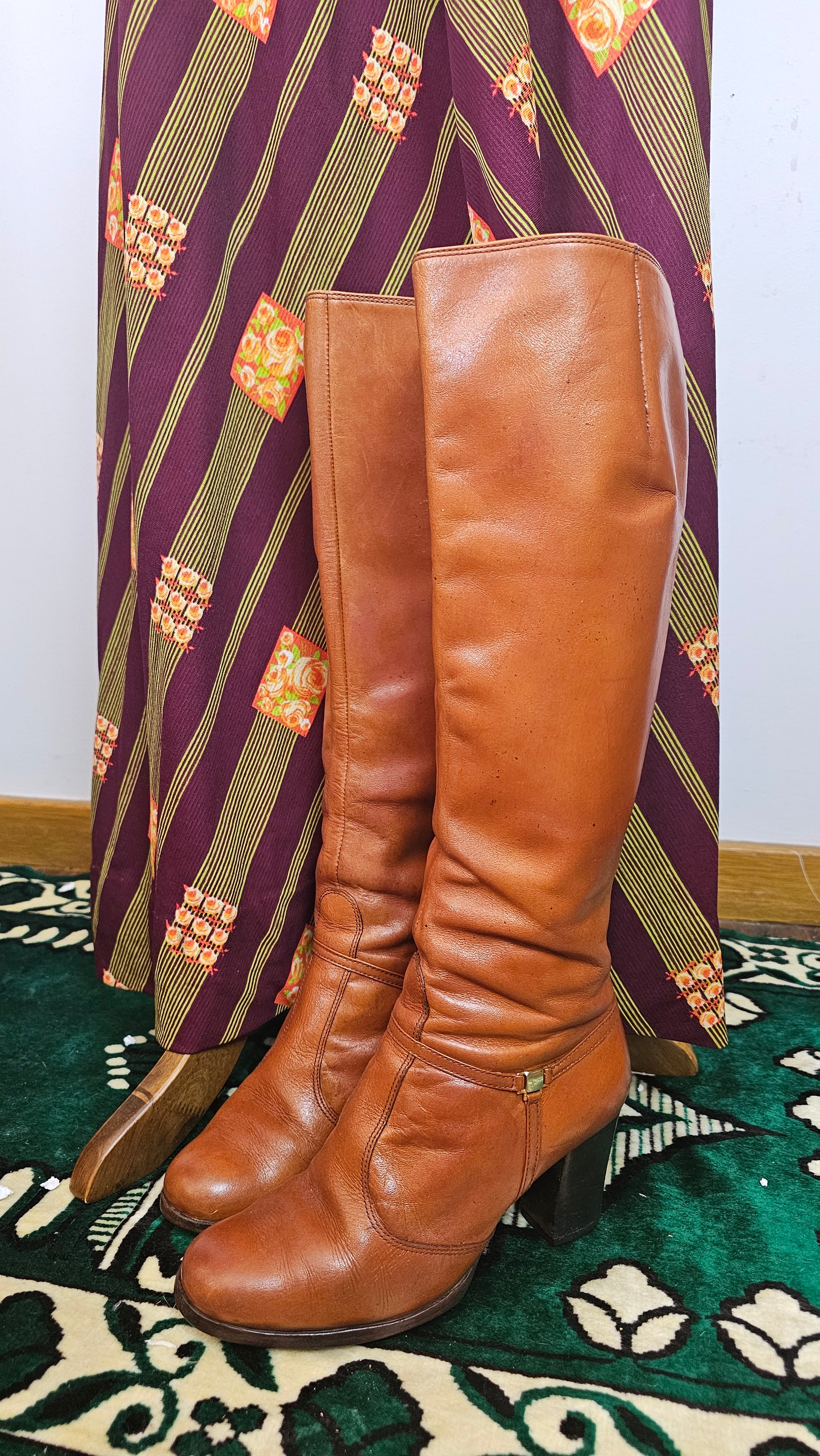 Brown leather knee-high boots on a patterned chair
