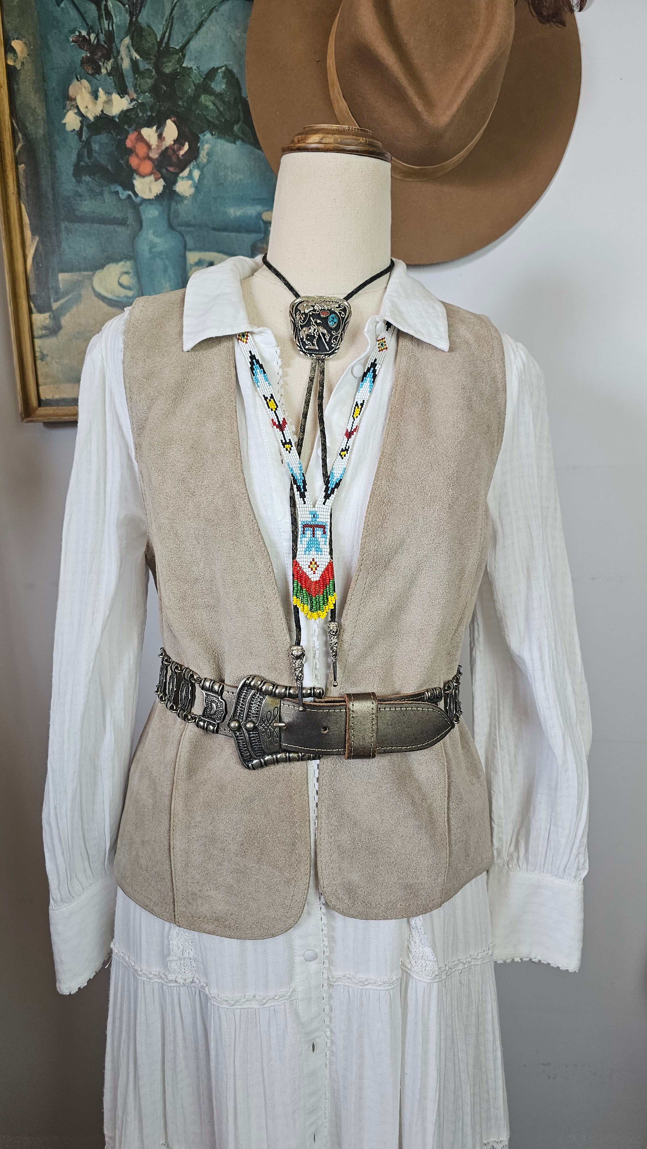 Mannequin wearing a traditional outfit with a hat and decorative sash on a plain background