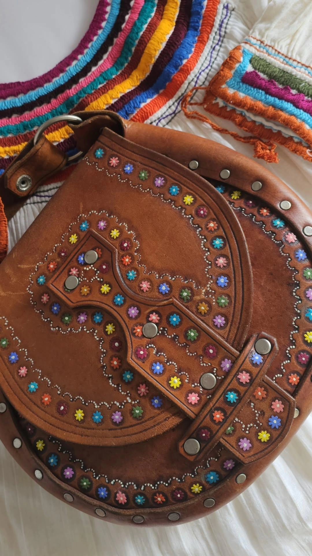 Brown leather bag with colorful embellishments on a white background