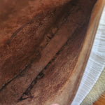 Brown leather glove with visible wear and tear, held by a hand.