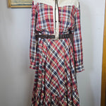 Plaid dress on a mannequin with a hat, against a white wall.