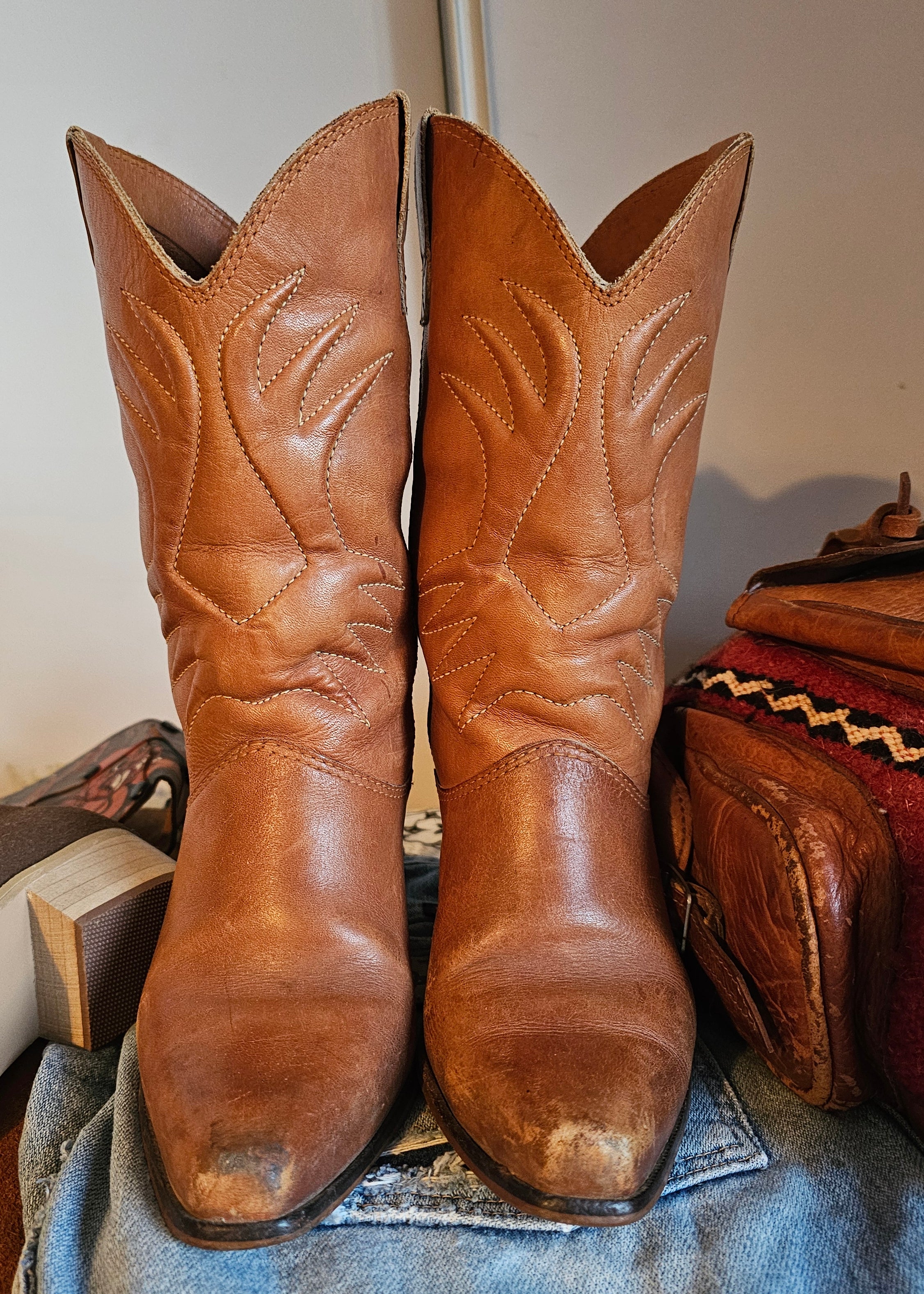 Vintage Brazilian Boots - Size 7B in tan leather with classic Western stitching, displayed front-facing on denim for a rustic 70s boots look.