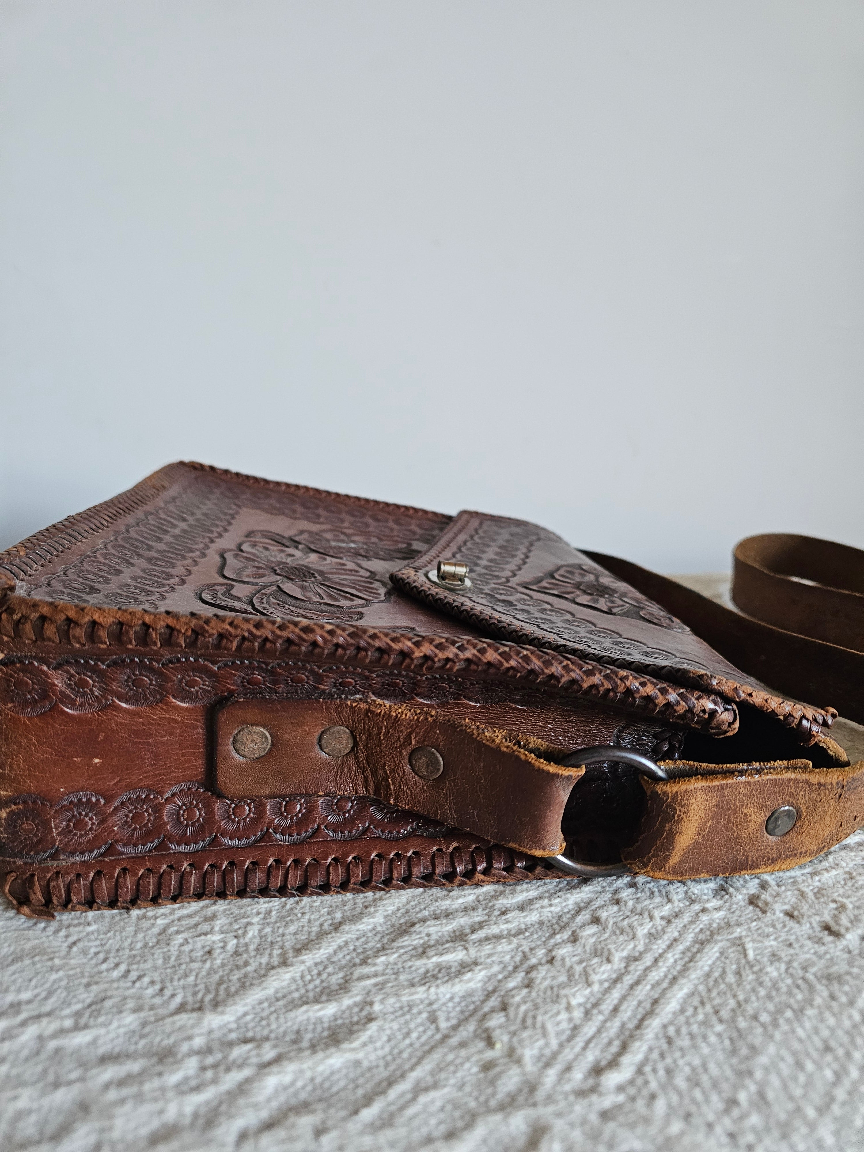 Brown leather bag with intricate designs on a textured surface