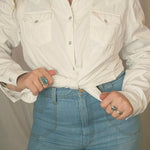 Person wearing a white jacket with decorative buttons on a plain background