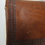 Brown leather handbag with decorative stitching on a white surface
