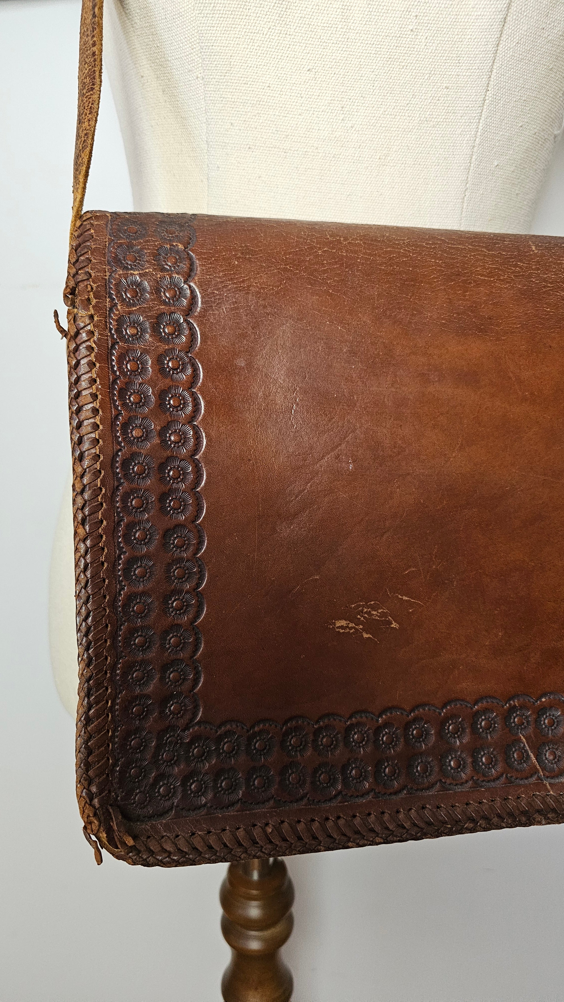 Brown leather handbag with decorative stitching on a white surface