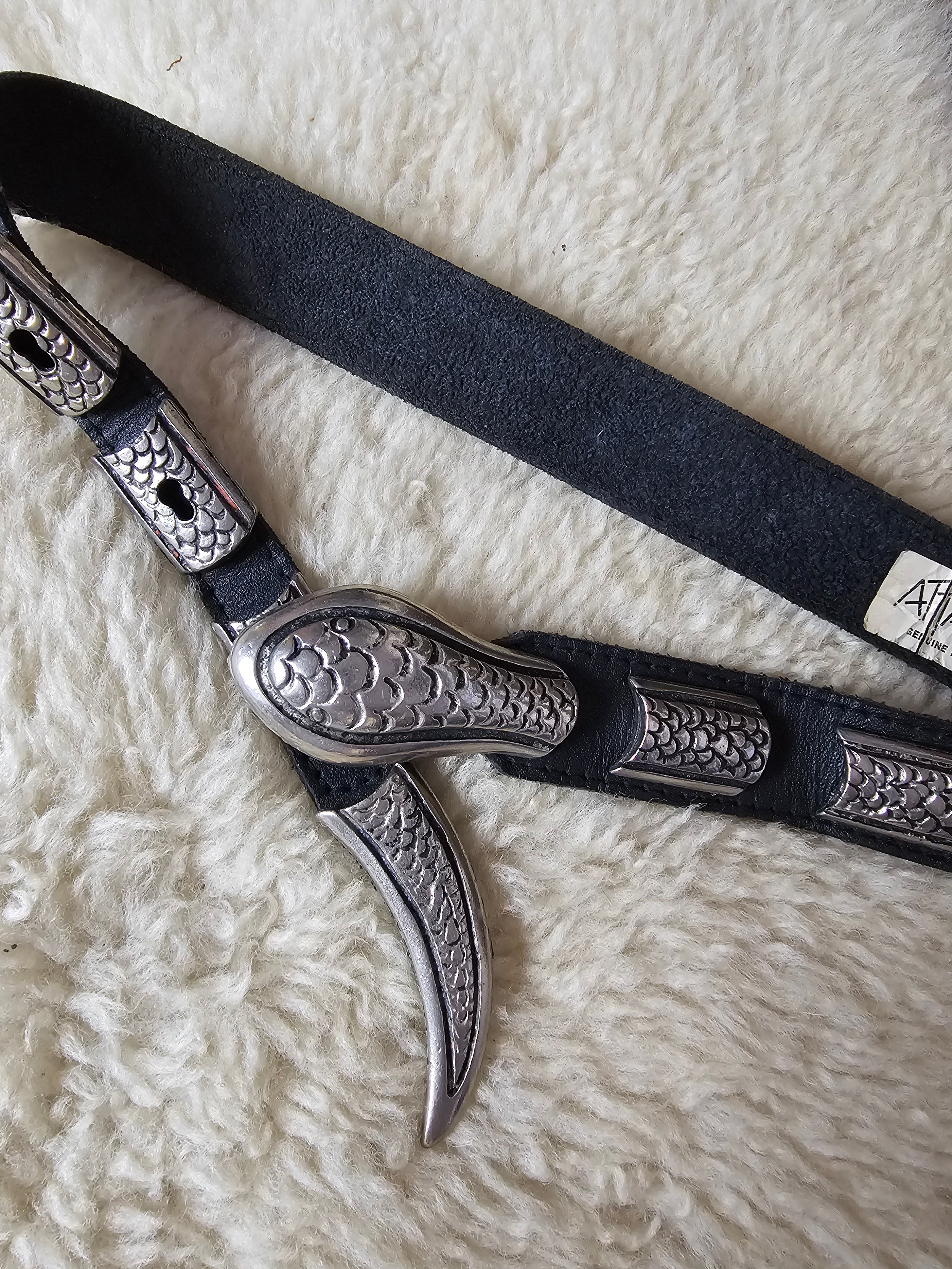 Decorative metal bridle bit with black leather strap on a textured surface