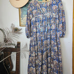 Property of Zephyr – Sienna Long Layer Dress hanging on wooden hanger, showing full length and intricate floral paisley design, size small.