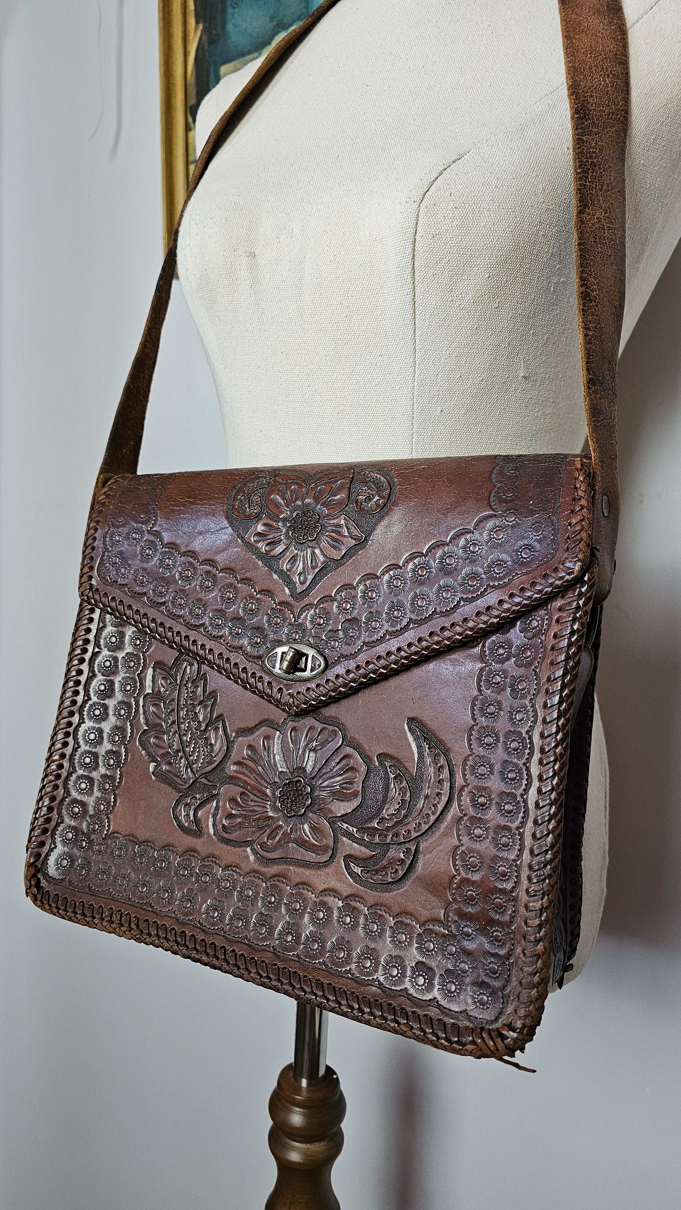 Brown leather handbag with floral embossing on a white surface