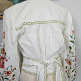 White embroidered dress on a mannequin with a brown hat and floral fabric in the background