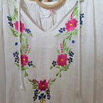 White fabric with floral embroidery on a wooden surface