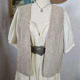 Mannequin wearing a beige trench coat with a hat and floral patterned fabric in the background