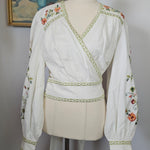 Traditional embroidered garment on a mannequin with a hat and fabric in the background