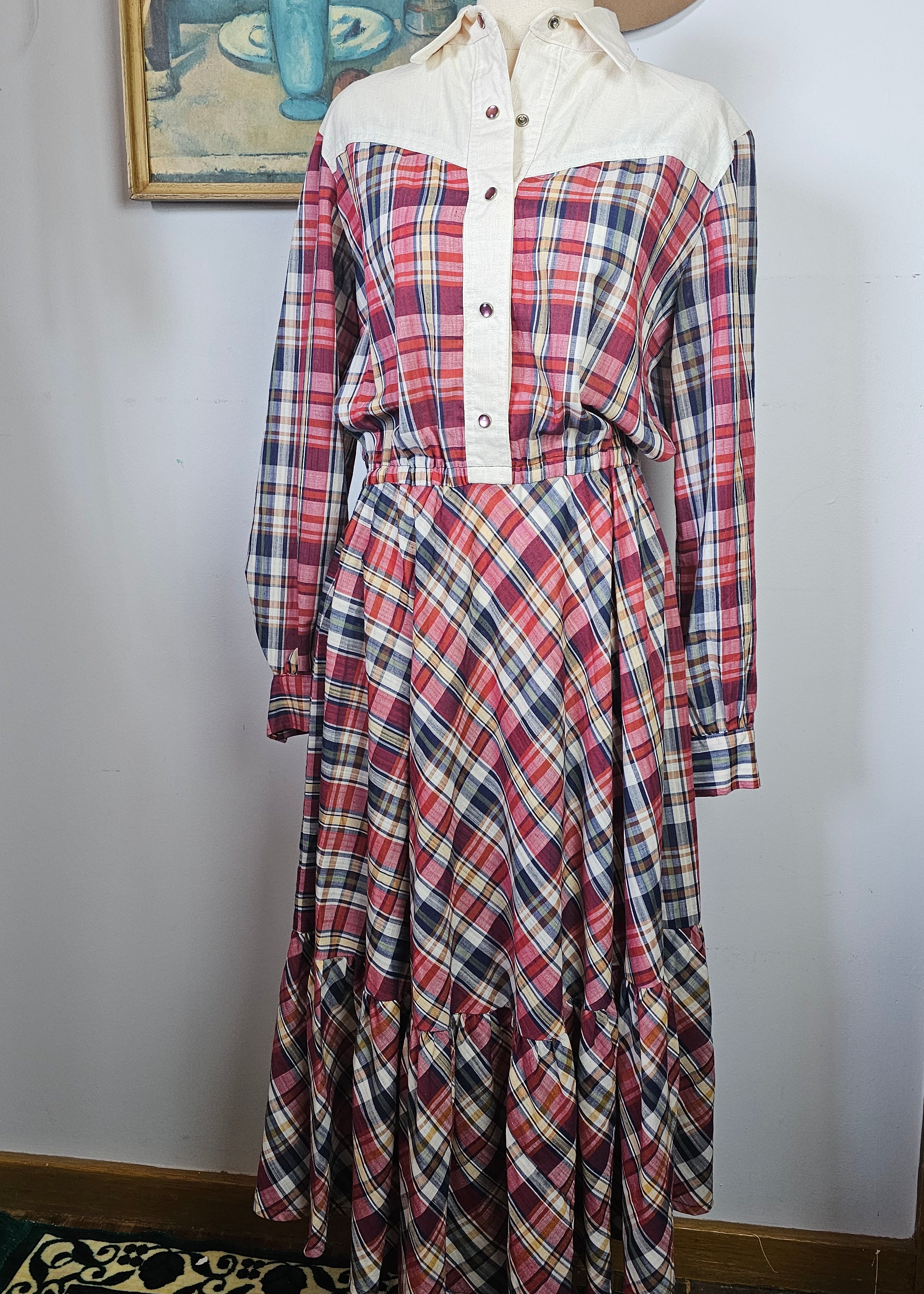 Plaid shirt on a mannequin against a white wall with decorative elements.