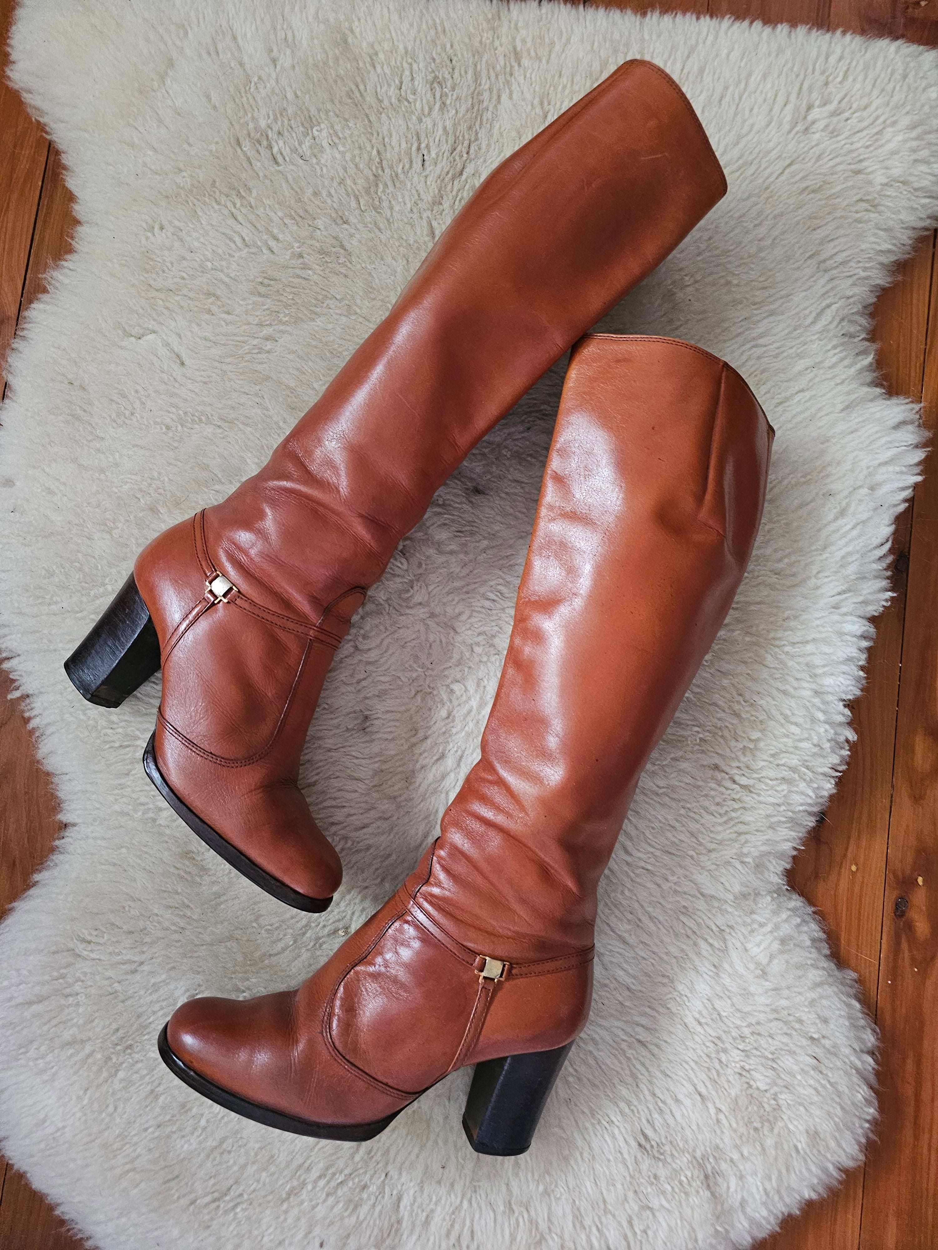 Pair of brown knee-high boots on a white fur rug