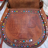 Brown leather saddle with colorful beadwork on a white background
