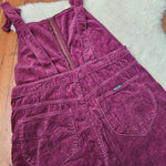 Purple corduroy dress on a wooden floor with a white rug underneath