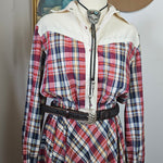 Plaid shirt with white jacket and brown hat on a surface