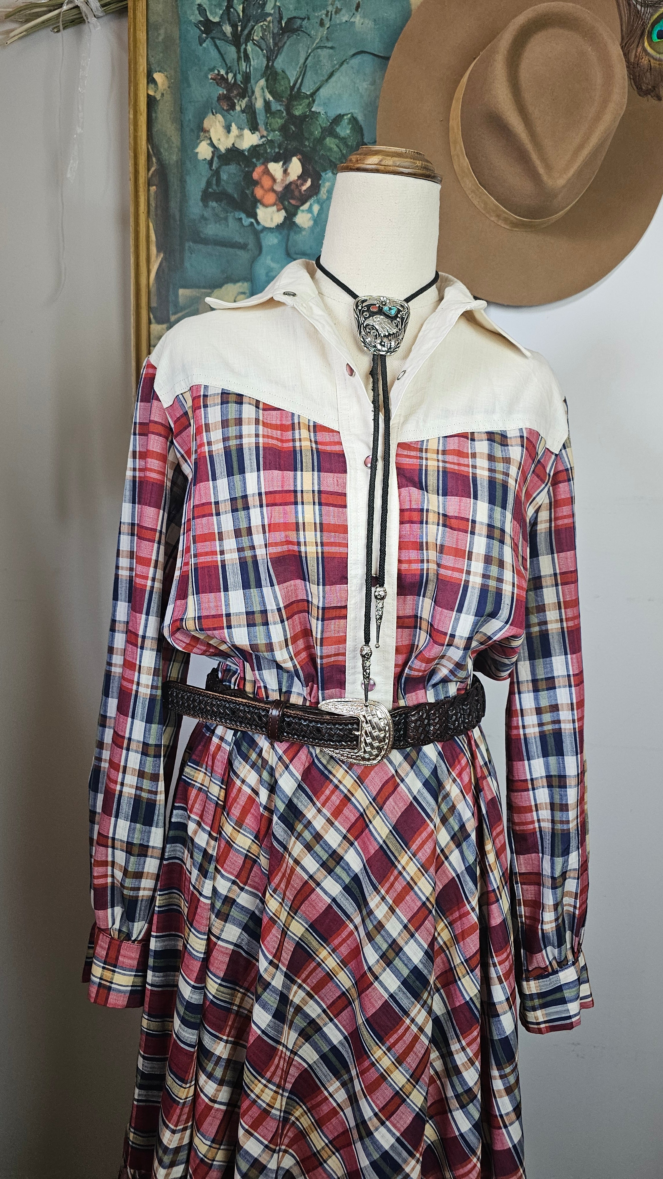 Plaid shirt with white jacket and brown hat on a surface