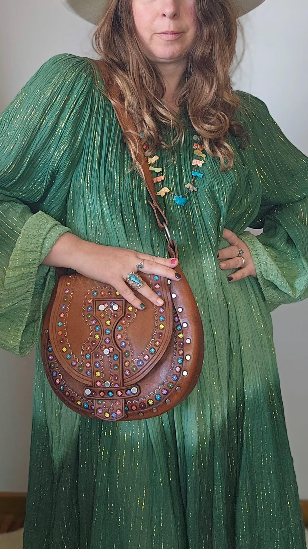 Person wearing a green dress holding a brown handbag with colorful embellishments.