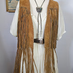 Mannequin wearing a long, fringed garment with a hat against a plain background