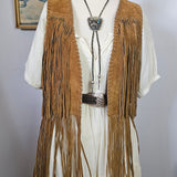 Mannequin wearing a long, fringed garment with a hat against a plain background